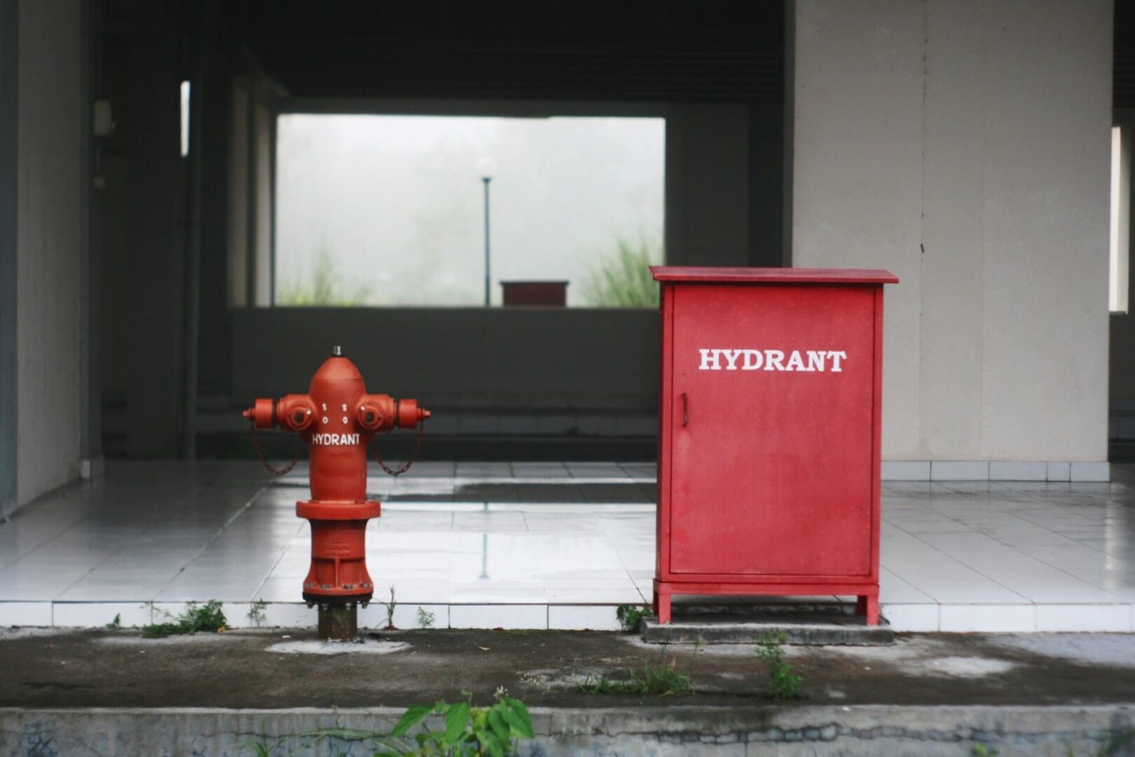A red fire hydrant next to a red cabinet.