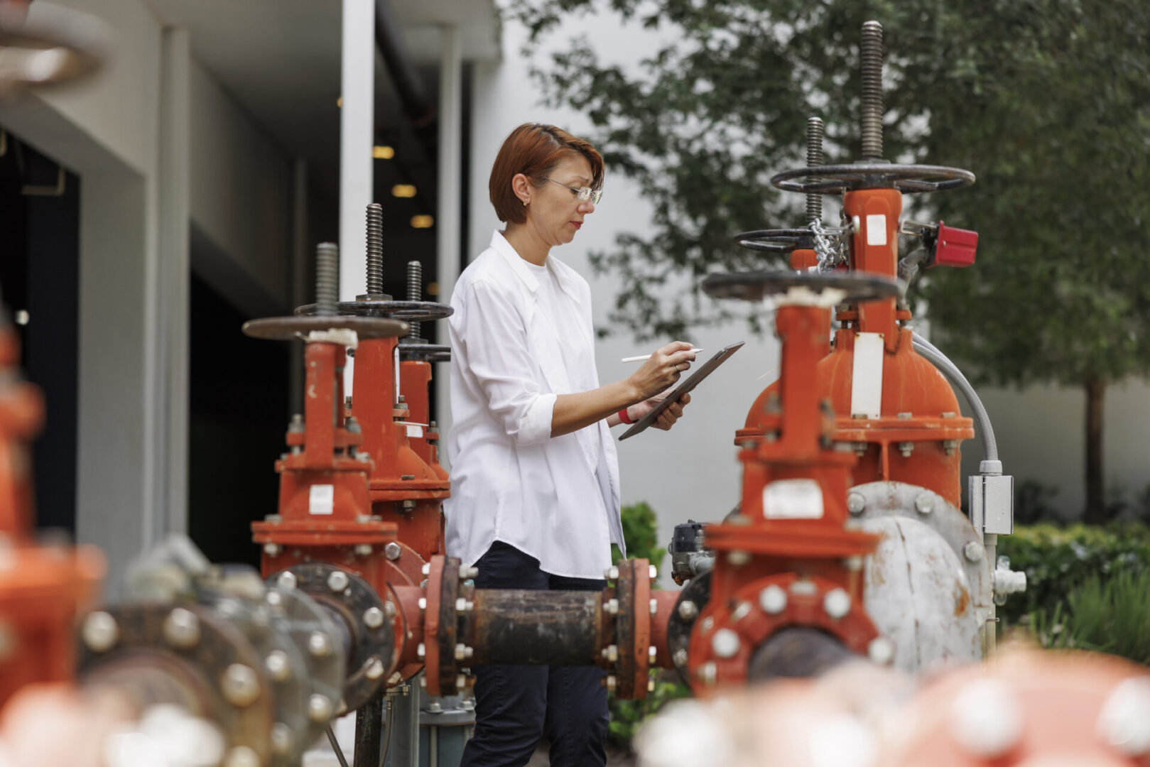 A woman is standing in front of some red pipes