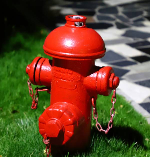 A red fire hydrant in the grass near a sidewalk.